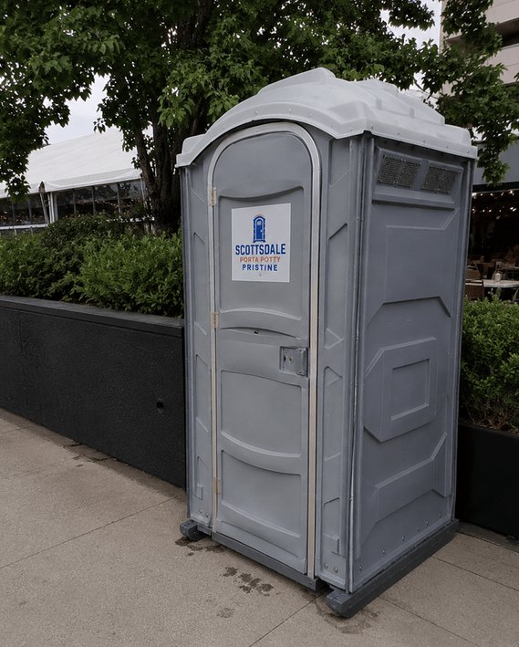 Deluxe flushing portable toilet rental placed on a paved area outside a venue